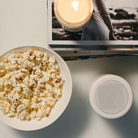 smart speaker with a candle and popcorn bol on a table